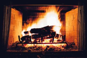 Cheminée ancienne qui refoule: feu vif dans une cheminée en briques, bois brûlant et flammes dorées, problèmes de tirage à diagnostiquer.