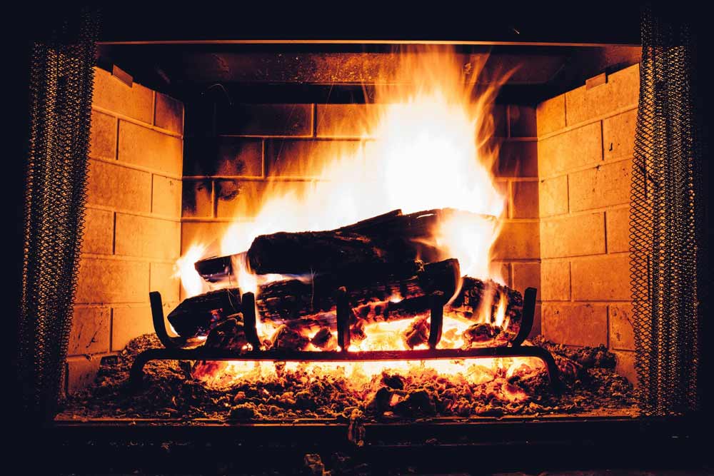 Cheminée ancienne qui refoule: feu vif dans une cheminée en briques, bois brûlant et flammes dorées, problèmes de tirage à diagnostiquer.