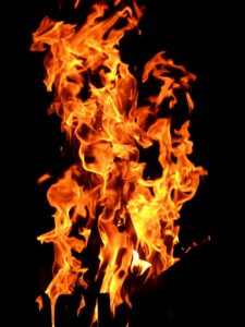 Flamme orange et jaune intense dans une cheminée sombre, suggérant un feu vif et dynamique à l’intérieur. Cheminée qui fume à lintérieur.