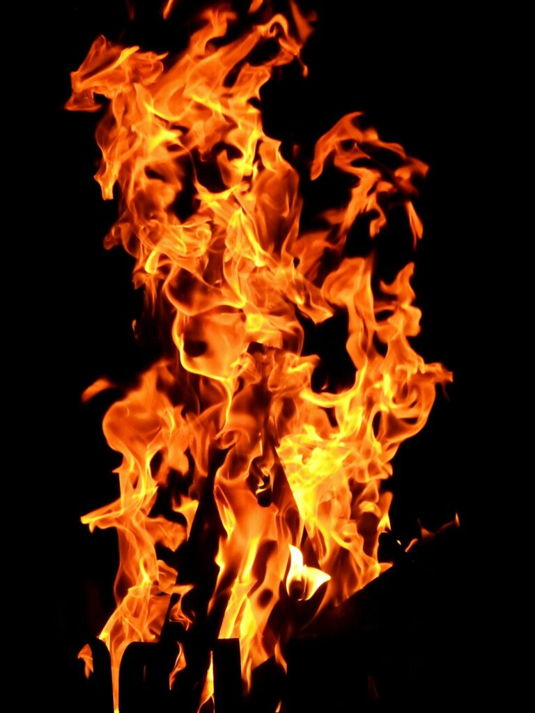Flamme orange et jaune intense dans une cheminée sombre, suggérant un feu vif et dynamique à l’intérieur. Cheminée qui fume à lintérieur.